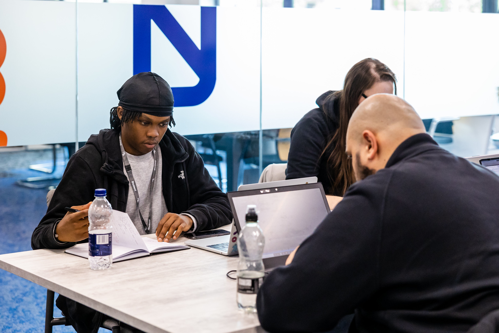 Students sat around a table working on laptops