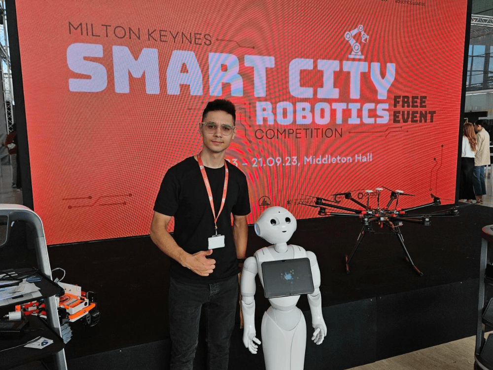 IoT students stood next to a white robot.