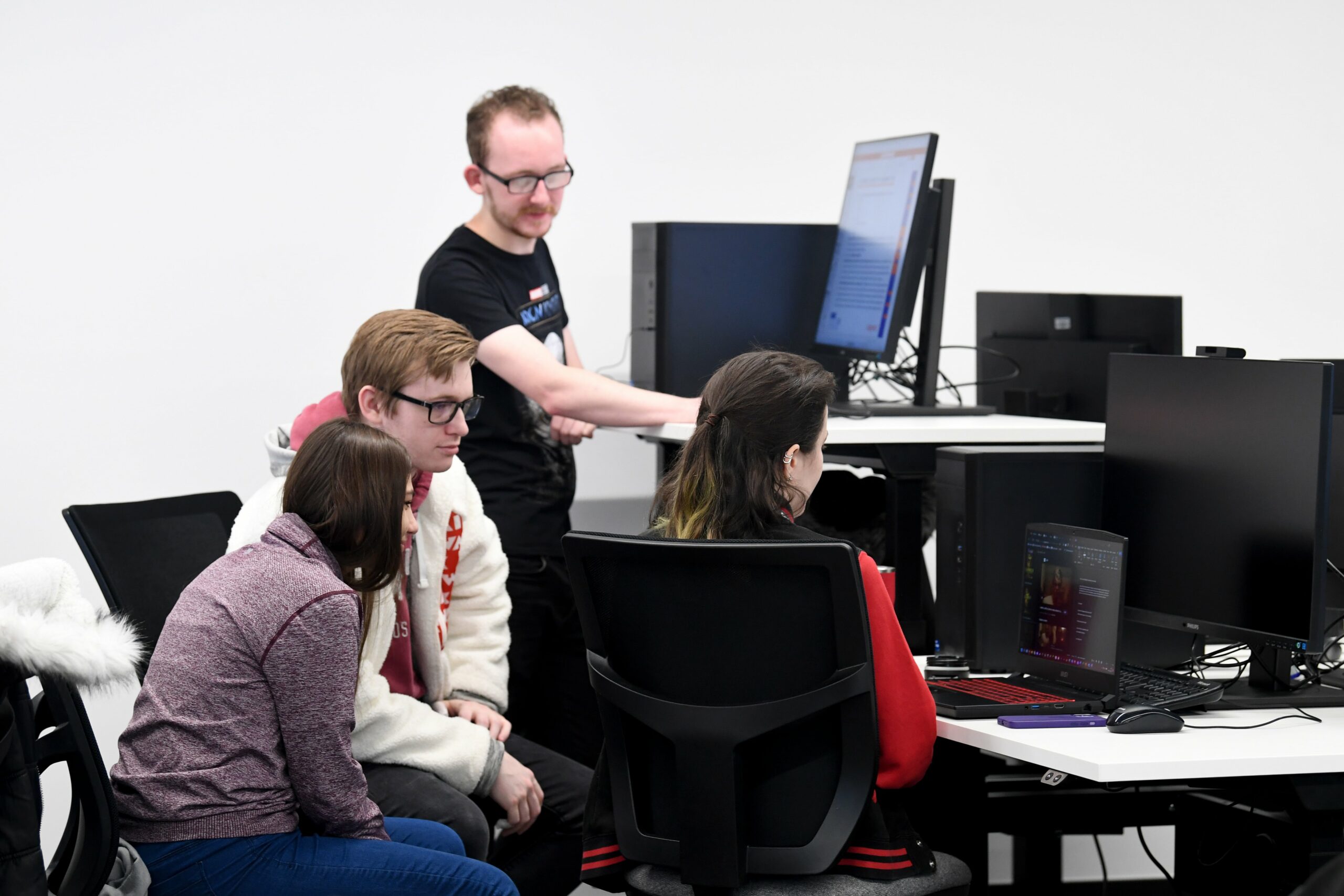 Students looking at a laptop screen with their teacher